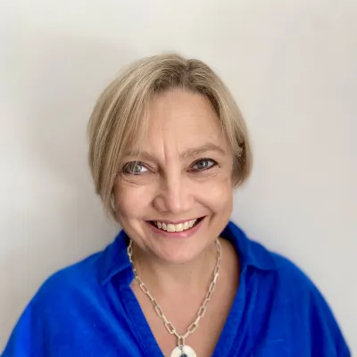 Professor Juliet Gray smiling at the camera with short blonde hair and wearing a blue blouse.