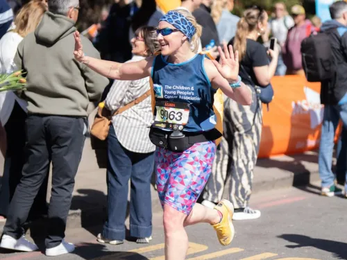 A woman smiling and running with a CCLG-branded t-shirt